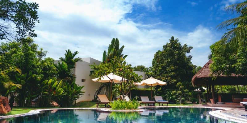 Inviting outdoor pool featuring sun loungers, a decorative umbrella, and a wooden deck