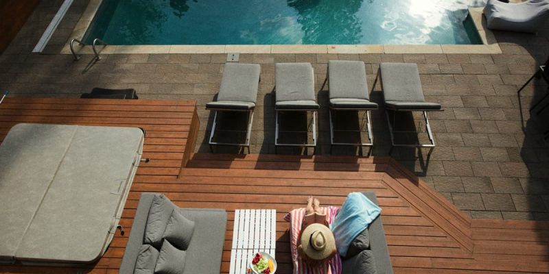 Crystal-clear pool surrounded by lush greenery and stylish lounge chairs under a shaded pergola