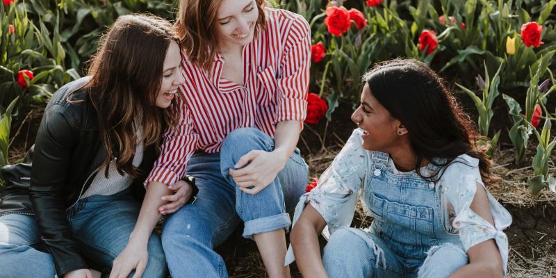 Friends enjoying a sunny picnic in a park, sharing food and laughter on a colorful blanket