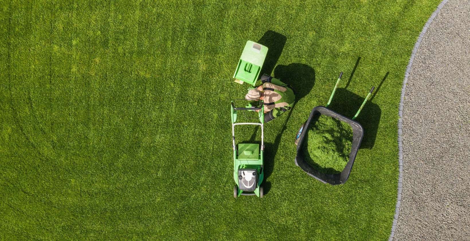 Person using a mower to cut grass in a well-maintained lawn